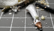 Bride and groom figurines lying at destroyed wedding cake on tiled floor